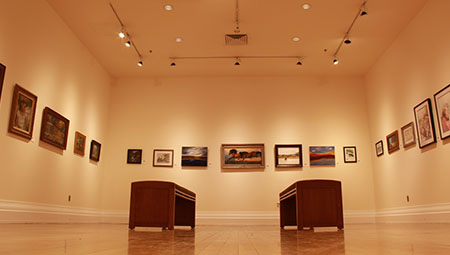 Artwork lines the walls and two benches sit in the middle of The Anderson art Gallery at the Provo Library